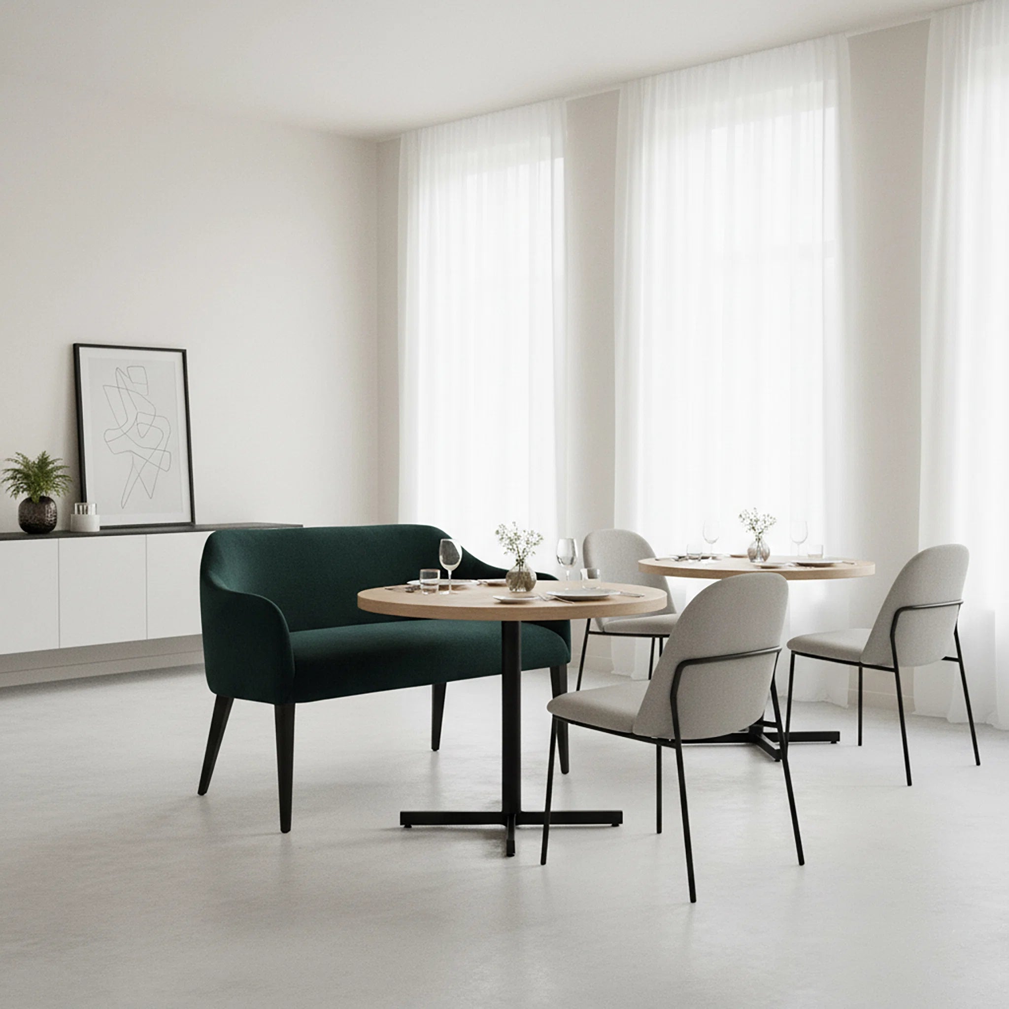 Modern dining area with a green sofa, round wooden table, and white chairs.