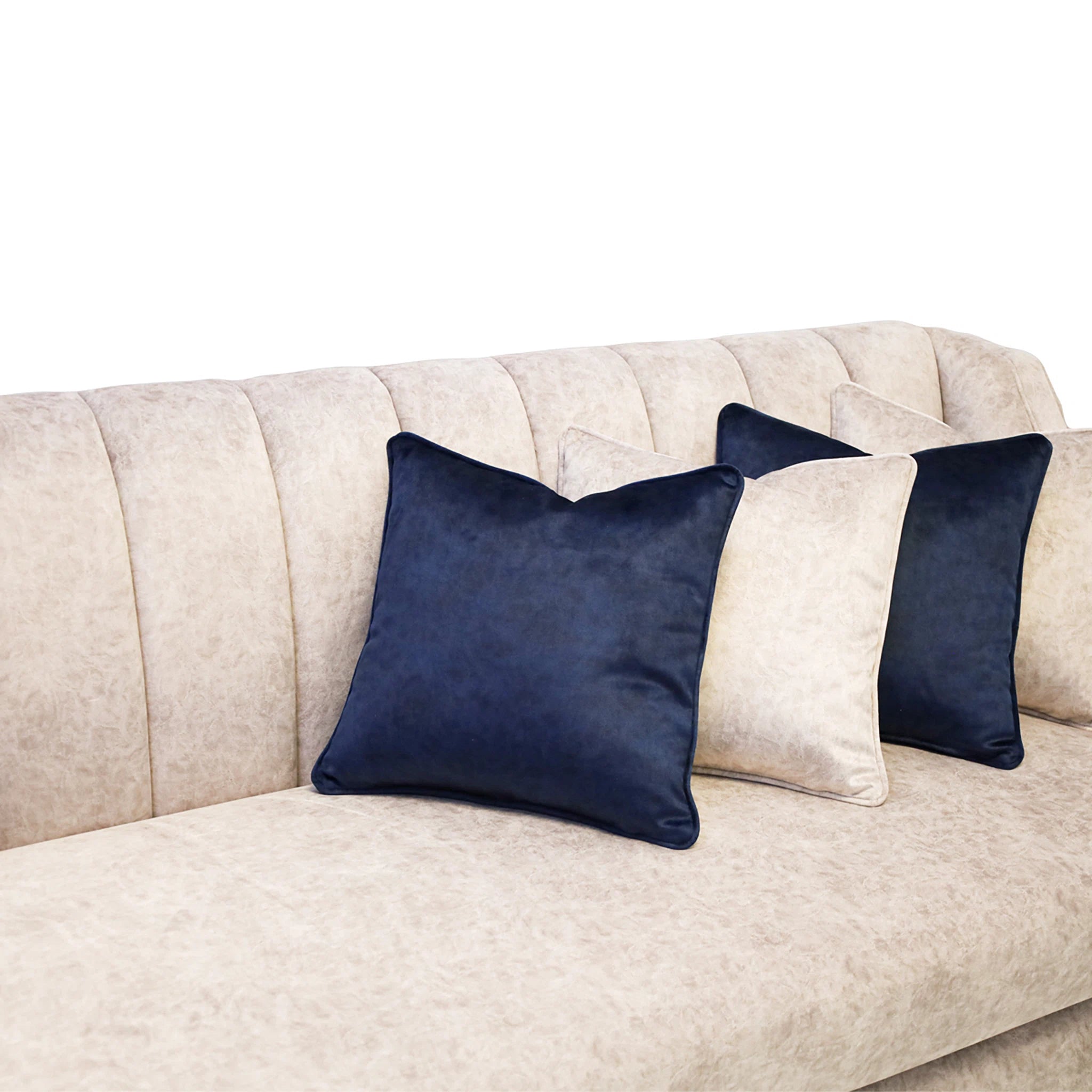 Navy blue pillows on a beige sofa against a white background