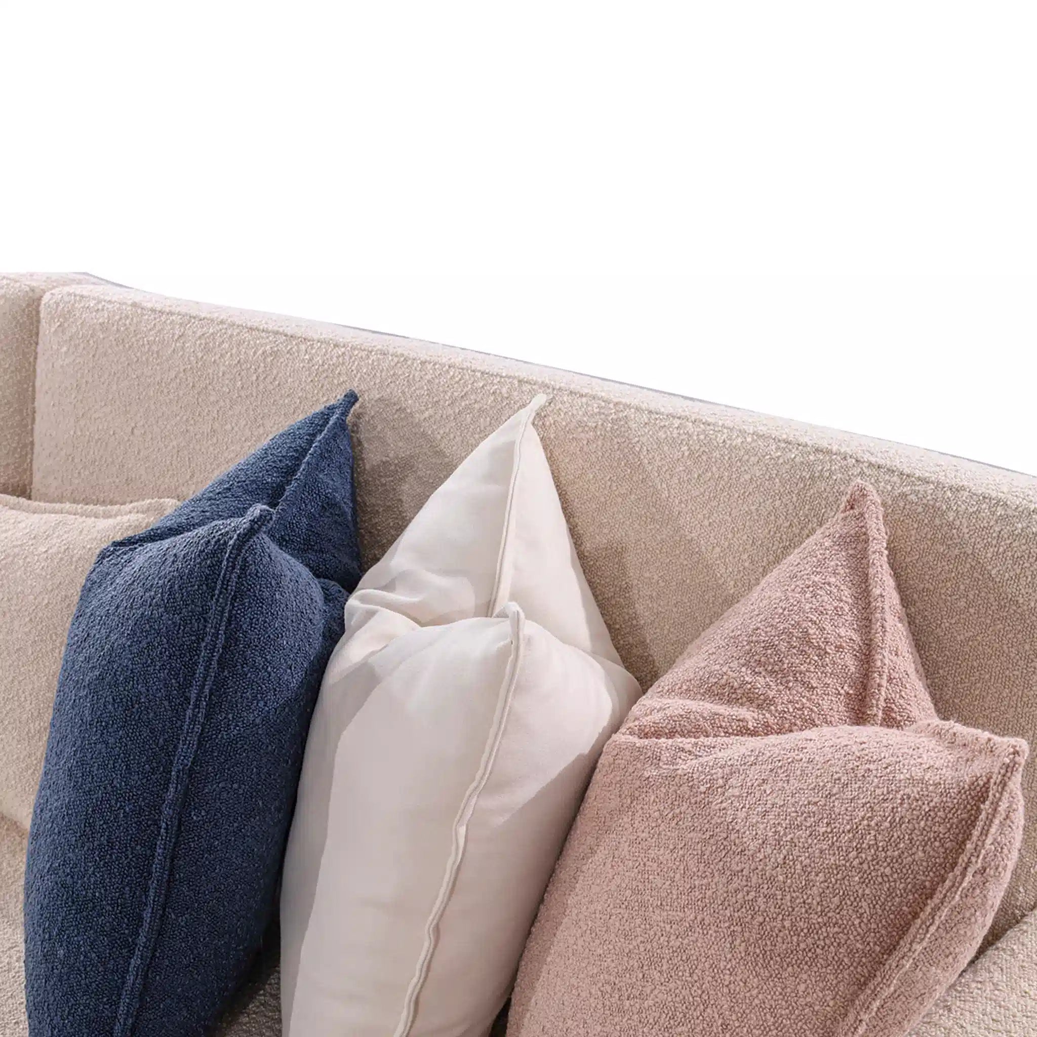 Beige sofa with blue, beige, and pink textured cushions on a white background