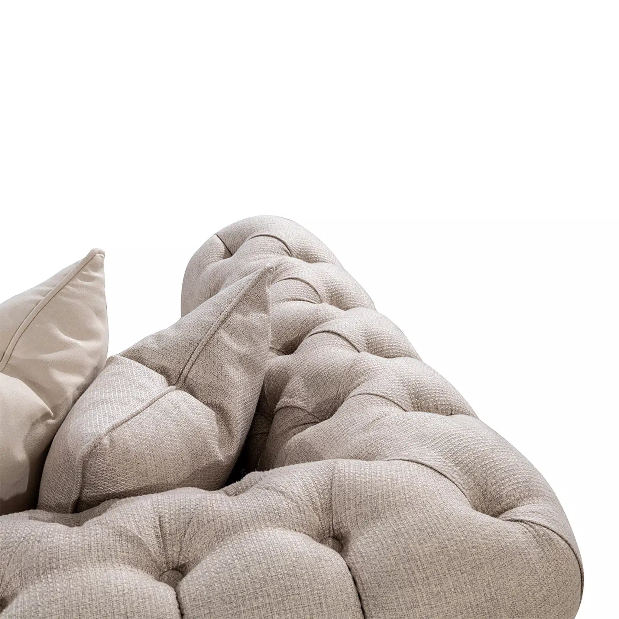 Close-up of a beige tufted sofa with cushions on a white background