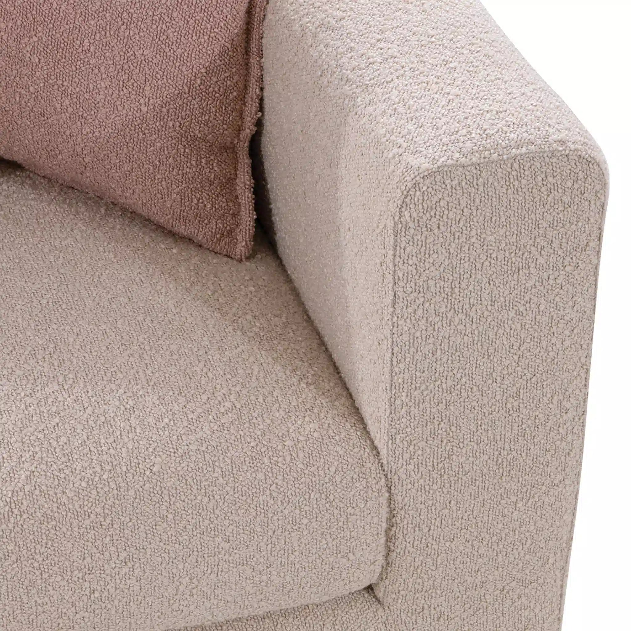 Close-up of a textured beige sofa with a pink pillow.