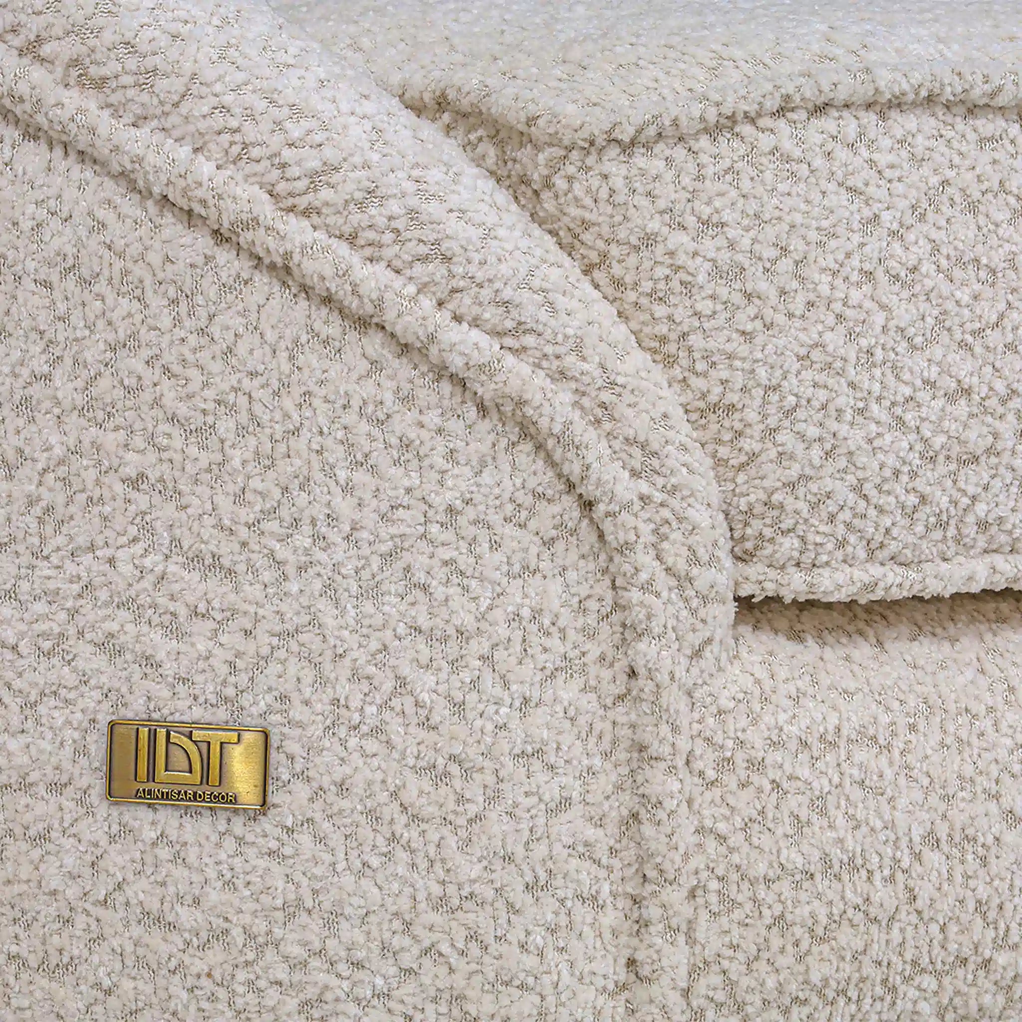 Close-up of a textured beige fabric with a gold label on a matching background