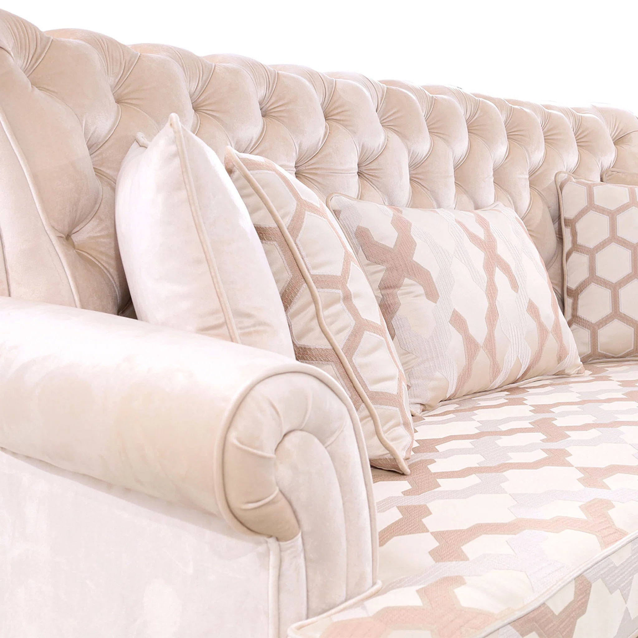 Beige tufted headboard with decorative pillows on a bed with patterned bedding.