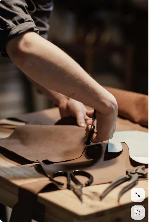 Person working with leather and tools on a wooden surface