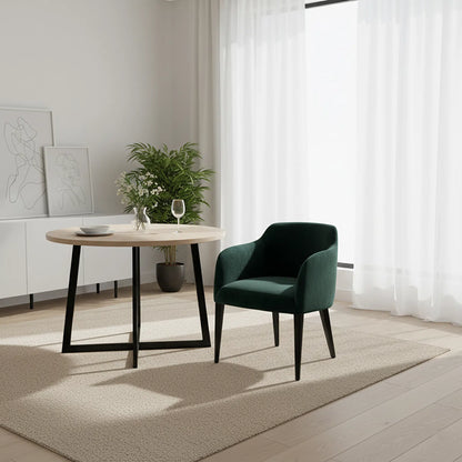 Modern interior with a round wooden table and green armchair near a window with white curtains.