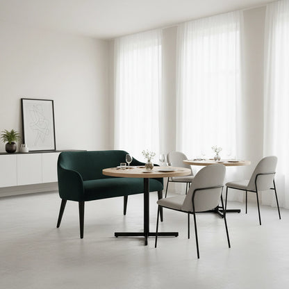 Modern dining area with a green sofa, round wooden table, and white chairs.