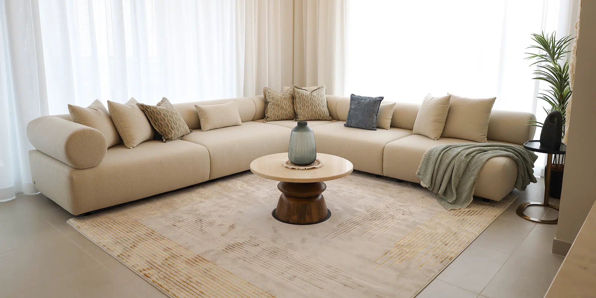 Beige sectional sofa in a living room with a wooden coffee table and decorative pillows.