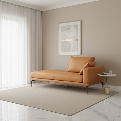 Modern living room with a tan leather chaise lounge, side table, and framed artwork.