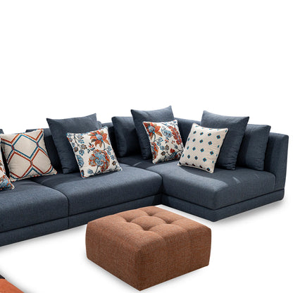 Blue sectional sofa with patterned cushions and a brown ottoman on a white background