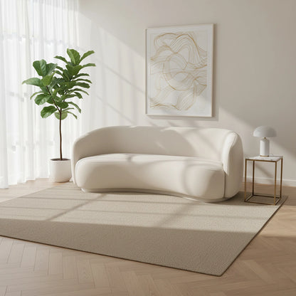 Modern living room with a white sofa, plant, and abstract art on the wall.