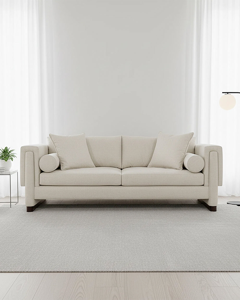 Beige sofa in a minimalistic room with white walls and light wood flooring.
