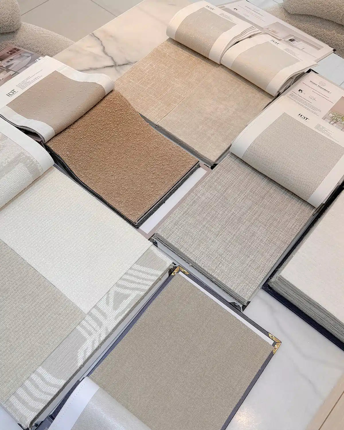 Collection of fabric swatches in neutral colors displayed in a book.