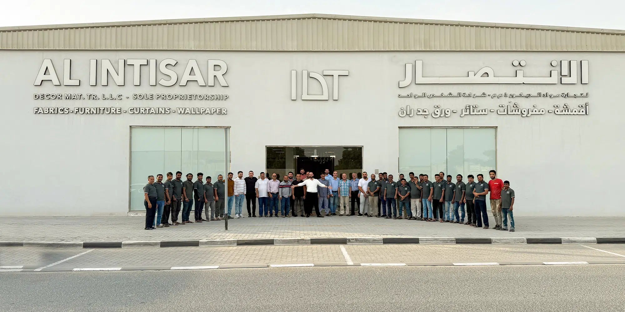 Group of people standing in front of a building with 'Al Intisar' branding.